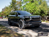 Front three-quarter view in sunlight of Rivian R2 with gloss black AW10 20x8.5 forged wheels and Michelin X-ICE SNOW 255/60 tires