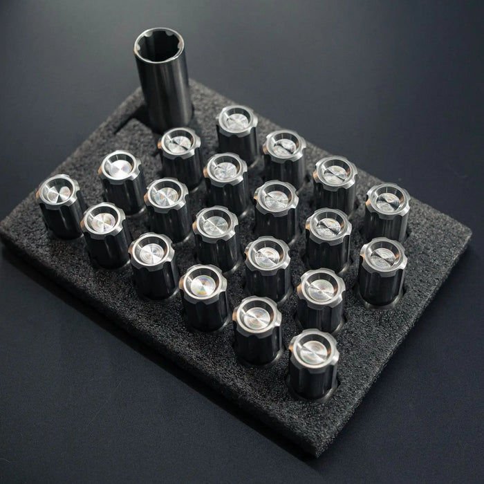 Set of metal nuts on a black foam block against a dark background