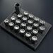 Set of metal nuts on a black foam block against a dark background